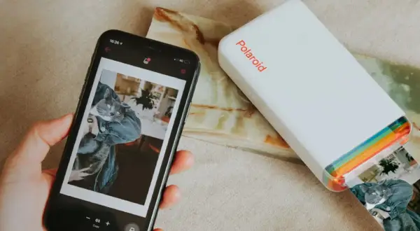 Jak wydrukować zdjęcie z telefonu? Smartfon z kotem i drukarka Polaroid w akcji.