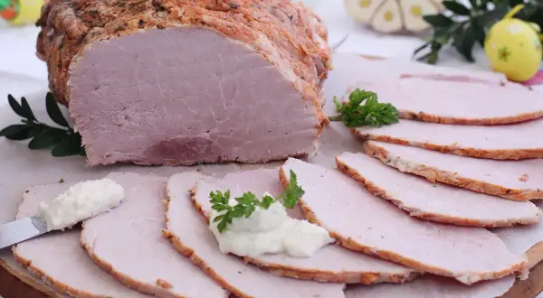 Pyszna szynka pieczona na obiad, pokrojona w plastry, podana z chrzanem i ziołami. Idealna na rodzinny posiłek.
