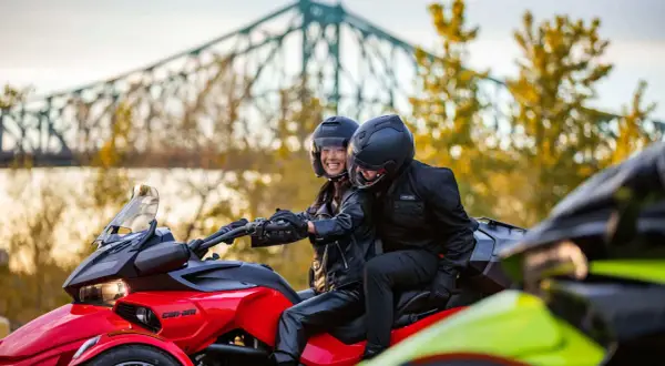 Para jadąca na czerwonym Can-Am Spyder, w tle most i jesienne drzewa.