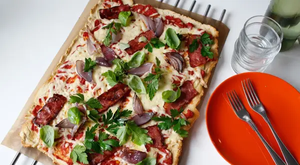 En läcker pizza med bacon och lök, toppad med färska örter och smält ost. Perfekt för en snabb och smakrik måltid.