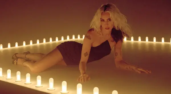 Miley Cyrus w stylizacji na "endless summer vacation" leży wśród rozświetlonych lamp.