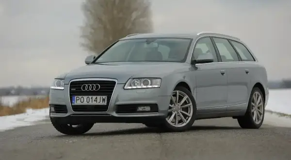 Szary Audi A6 C6 kombi na drodze. Zbliżenie na przód auta, widoczne światła, grill i tablica rejestracyjna. Wymiary tego modelu są idealne dla rodziny.