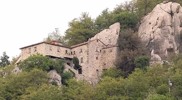 Antica pieve in pietra a Pieve Santo Stefano, incastonata tra rocce e alberi secolari, testimone di storia.