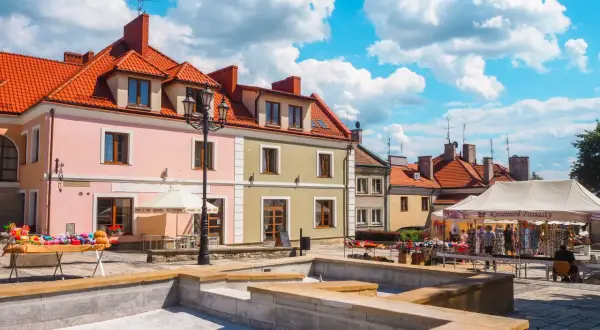 Sandomierz rynek tętni życiem. Kolorowe kamienice, stragany z pamiątkami i błękitne niebo tworzą malowniczy widok.