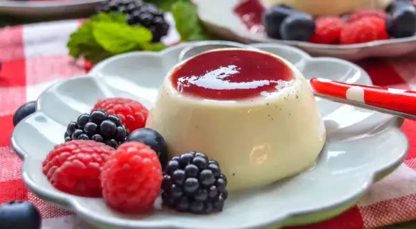 Cremige Panna Cotta mit Beeren und roter Soße, ein Genuss für Augen und Gaumen.