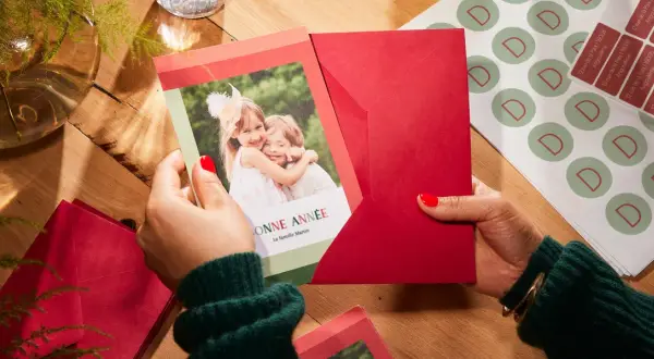 Préparation de textes de noël familial : une carte avec deux enfants souriants et des enveloppes rouges.