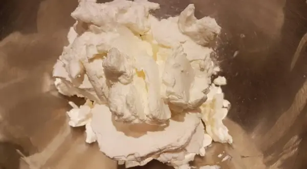 Krem z mascarpone w metalowej misce, gotowy do ubijania.