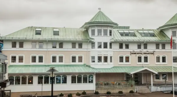 Home Hotel Fregatten i Varberg, med sitt gröna tak och ljusa fasad, välkomnar gäster.