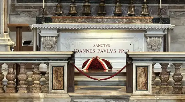 Grób Jana Pawła II w Watykanie. Marmurowa płyta z napisem "Sanctus Ioannes Paulus PP. II" i wieniec z czerwonych róż.