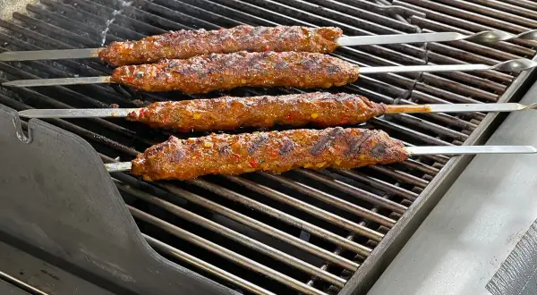 Vier saftige Adana Kebap Spieße brutzeln auf dem Grill. Das perfekte Adana Kebap Rezept für den Sommer.