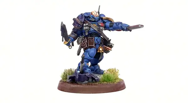 Błękitny Space Marine z mieczem i toporem, gotowy do walki. To zdjęcie na studia, ukazujące szczegóły figurki.