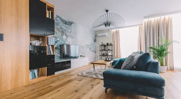 Nowoczesny salon z sofą w odcieniach turkusu i szarości, gdzie dominują zimne kolory. Marmurowa ściana dodaje elegancji.