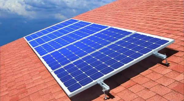 Paneles solares azules sobre un tejado rojo, capturando la energía del sol. ¿Quién inventó las placas solares?