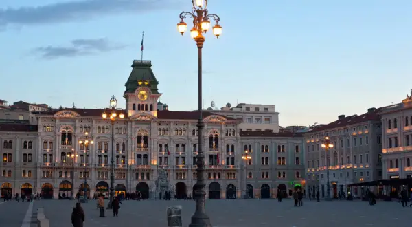 Piazza Unità d'Italia a Trieste, con i suoi palazzi illuminati e un cielo crepuscolare.
