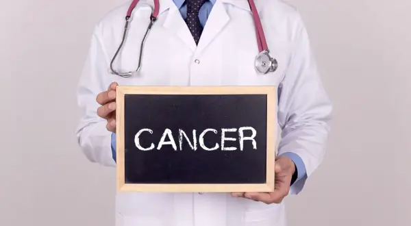 Lekarz w białym kitlu trzyma tabliczkę z napisem "CANCER". Co to znaczy nowotwór low grade?