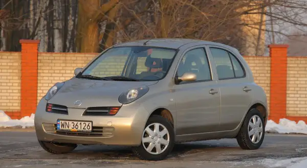 Złoty Nissan Micra K12 z nowymi żarówkami, gotowy na zimowe drogi.