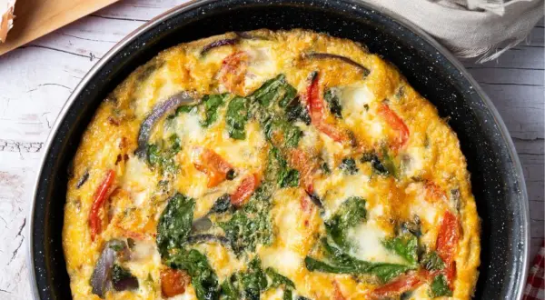 Pyszny omlet z cukinią, szpinakiem i pomidorami, zapieczony w patelni. Idealny na śniadanie lub lekki obiad.