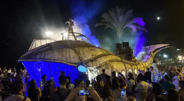 Una gran ballena mecánica ilumina la noche en una fiesta de los 90 en Zaragoza. El público, con móviles en mano, celebra el espectáculo.