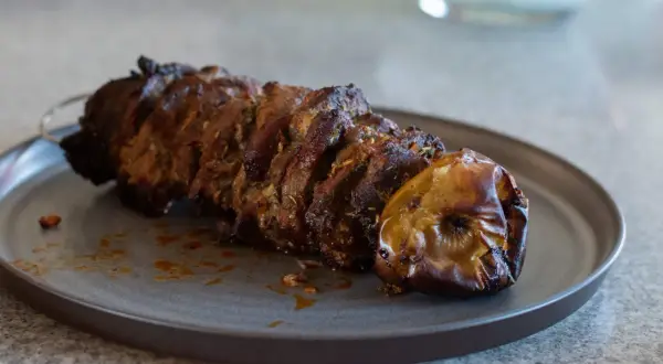 Saftigt kött på spett, perfekt för ett gyros recept. En ugnsbakad äpple ligger bredvid.