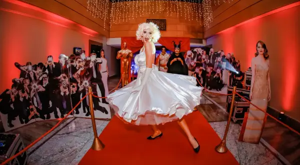Kobieta w sukni Marilyn Monroe na czerwonym dywanie, otoczona wycinankami gwiazd i paparazzi. Prawdziwa styl hollywood impreza!