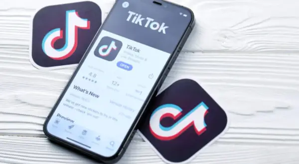 Telefon z aplikacją TikTok i logotypy platformy. Zastanawiasz się, ile zarabia się na tiktoku za 1000 wyświetleń?