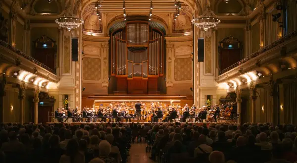 Ein Orchester spielt im prunkvollen Saal des Opernhauses Wuppertal vor einem begeisterten Publikum.