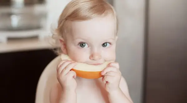 Ein süßes Baby genießt ein Stück Honigmelone.
