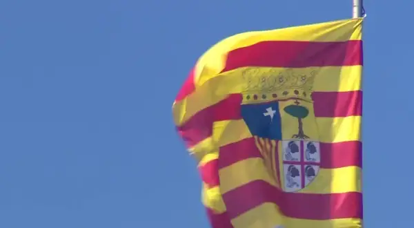 Bandera de San Jorge de Aragón ondeando con orgullo contra el cielo azul.