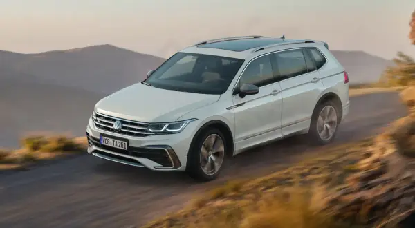Biały Volkswagen Tiguan Allspace przemierza górską drogę.