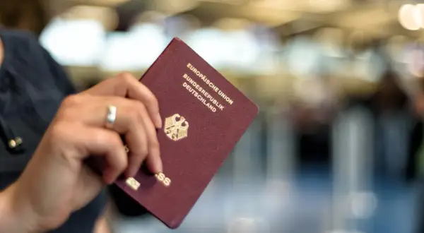 Ein deutscher Reisepass, der nass geworden ist, wird von einer Hand gehalten. Die Seiten sind leicht gewellt.