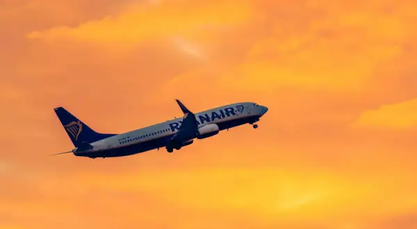 Samolot Ryanair wznosi się na tle pomarańczowego nieba. Idealny na krótkie wycieczki 4 dniowe samolotem.
