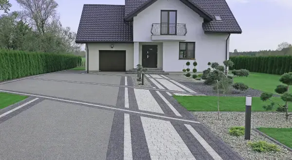 Nowoczesny podjazd z kamienia prowadzi do białego domu z garażem.