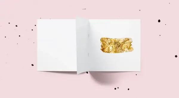 Otwarta biała kartka z fragmentem folii w kolorze **złota**.