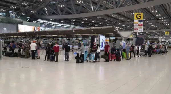 Menschen stehen in einer Schlange am Flughafen-Check-in. Gute **Kiwi com Erfahrungen** sind wichtig für entspanntes Reisen.