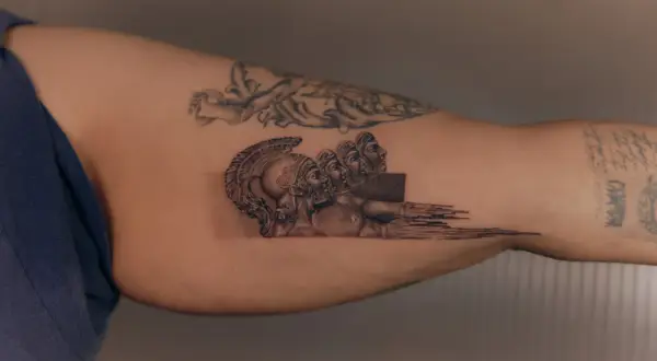 Tatuaż mikrorealizm przedstawiający antyczne hełmy i twarze, zlewające się w abstrakcyjny wzór.