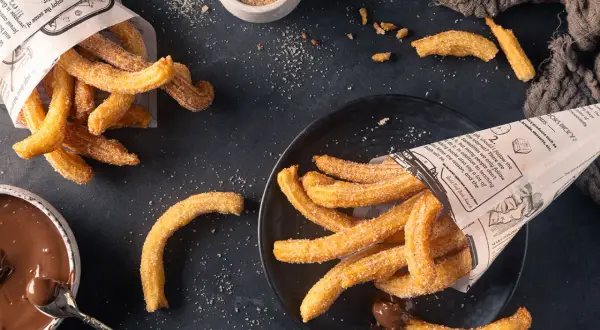 Frisch frittierte Churros, mit Zucker bestreut, serviert mit Schokoladensauce. Perfekt zum Churros selber machen!
