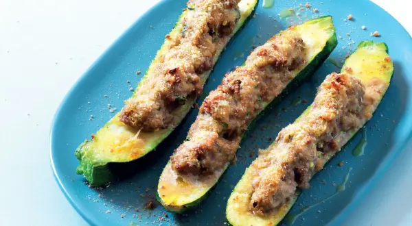 Zucchine tonde ripiene di carne, cotte al forno e servite su un piatto blu.