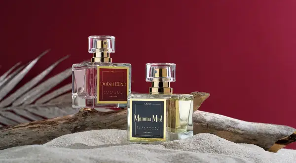 Dwa flakoniki perfum z feromonami, "Dubai Elixir" i "Mamma Mia!", na piasku i drewnie. Czy perfumy z feromonami działają?
