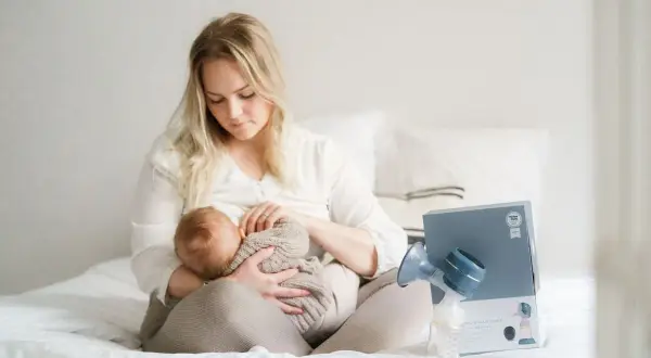 En mamma ammar sitt lilla barn. Bredvid dem står en bröstpump och dess förpackning.