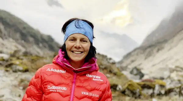Kristin Harila, bereit für den K2, lächelt in die Kamera, umgeben von majestätischen Bergen.