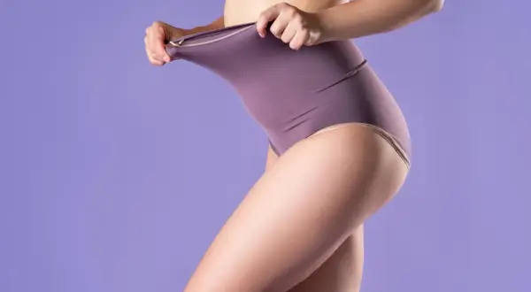 Kobieta pokazuje elastyczność bielizny typu shapewear, która modeluje sylwetkę.