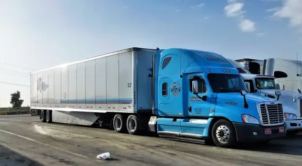 Błękitna ciężarówka Gordon Trucking z naczepą, gotowa do podróży door to door.