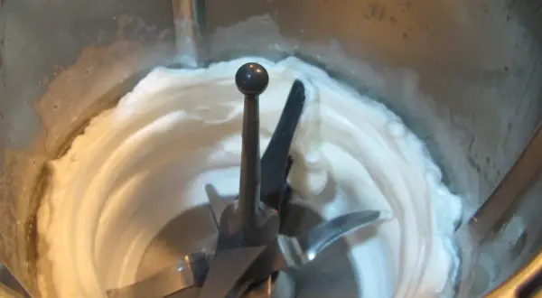 Batidora procesando claras a punto de nieve, creando una textura esponjosa y blanca, lista para un postre.