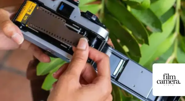 Hands loading a 36-exposure film into a vintage camera. The film roll is visible, ready to capture memories.