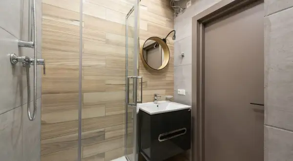 Modernos baños pequeños con ducha, lavabo flotante y espejo redondo.
