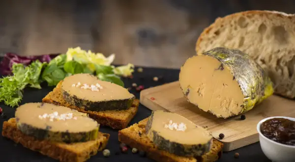 Tranches de foie gras sur toasts, accompagnées de salade verte, pain frais et confiture. La cuisson du foie gras est parfaite.