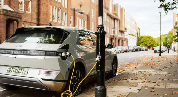 Coches eléctricos noticias: un Hyundai Ioniq 5 cargando en una calle de Londres, con edificios de ladrillo y hojas caídas.