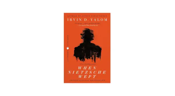 Okładka książki "Gdy Nietzsche płakał" Irvina D. Yalom z czarną sylwetką na pomarańczowym tle.