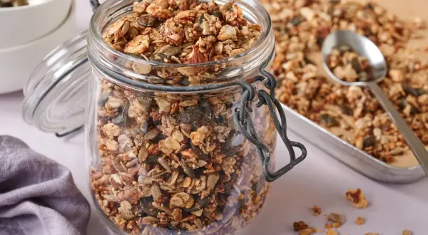 Ein Glas voller knusprigem, selbstgemachtem Granola ohne Zucker, mit Nüssen und Kernen. Perfekt für ein gesundes Frühstück.