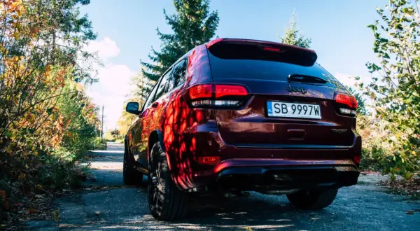 Ciemnoczerwony Jeep Grand Cherokee Trackhawk na tle jesiennego krajobrazu.